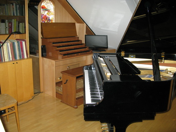 Im Hintergrund der Orgelspieltisch mit dem Glasfenster vom Rattenfänger zu Hameln, vordergründig der Konzertflügel.